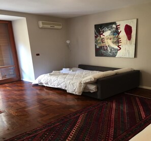 A bedroom with a bed, a wall-mounted air conditioner, a floor lamp, and a large abstract painting. - MANETTI ROOMS Double Room on Via Chiaia, 600 meters from the waterfront. (Napoli)
