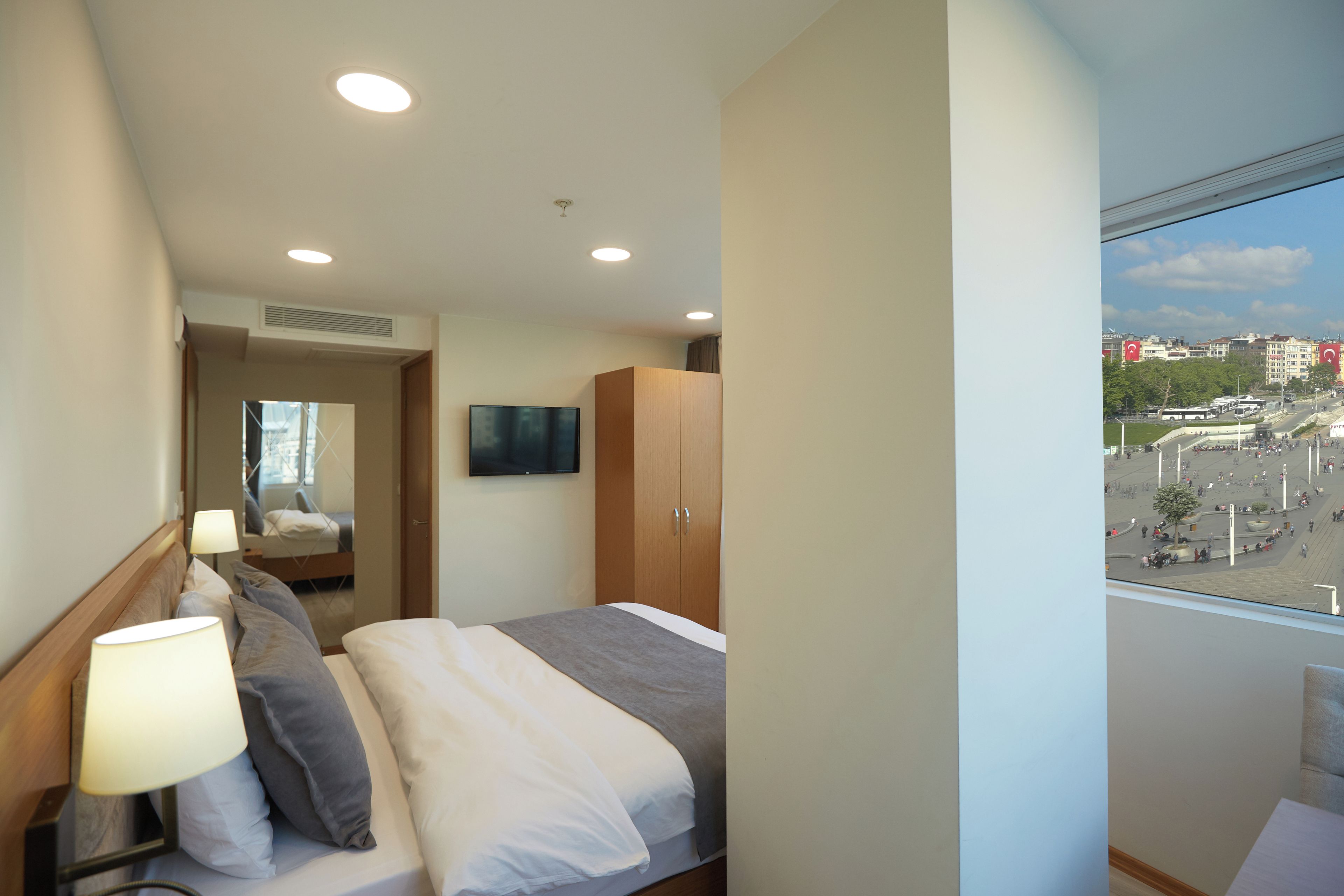 Una camera d'albergo con un letto, una TV, un armadio e vista sulla città.