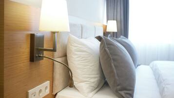 A hotel room with a wooden headboard, a bedside lamp, and a bed with white and gray bedding.