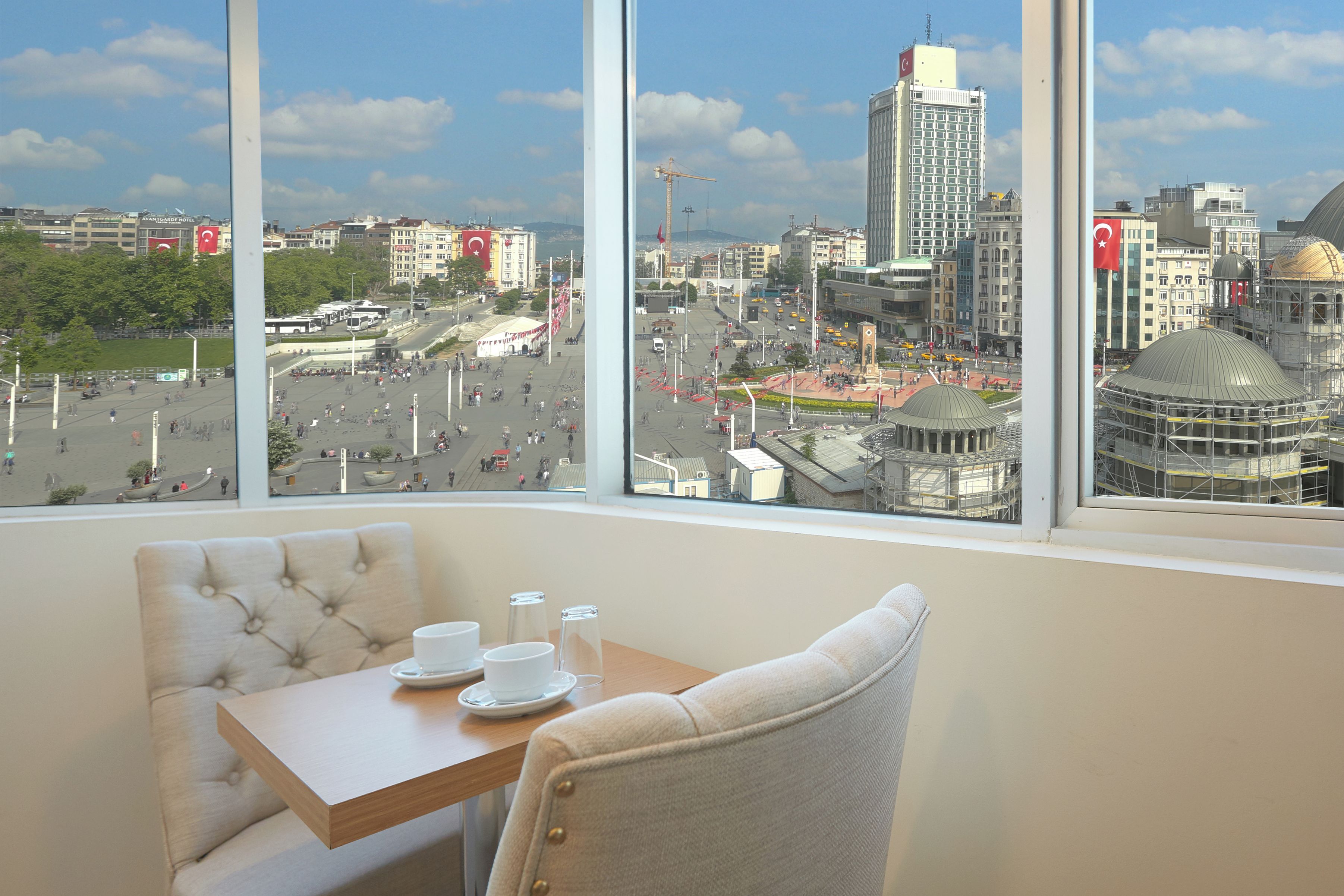 A hotel room with a large window offering a view of a cityscape, including a prominent building with a dome.