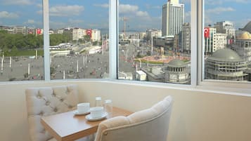 A hotel room with a large window offering a view of a cityscape, including a prominent building with a dome.