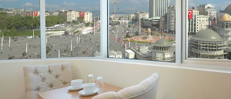 A hotel room with a large window offering a view of a cityscape, including a prominent building with a dome.
