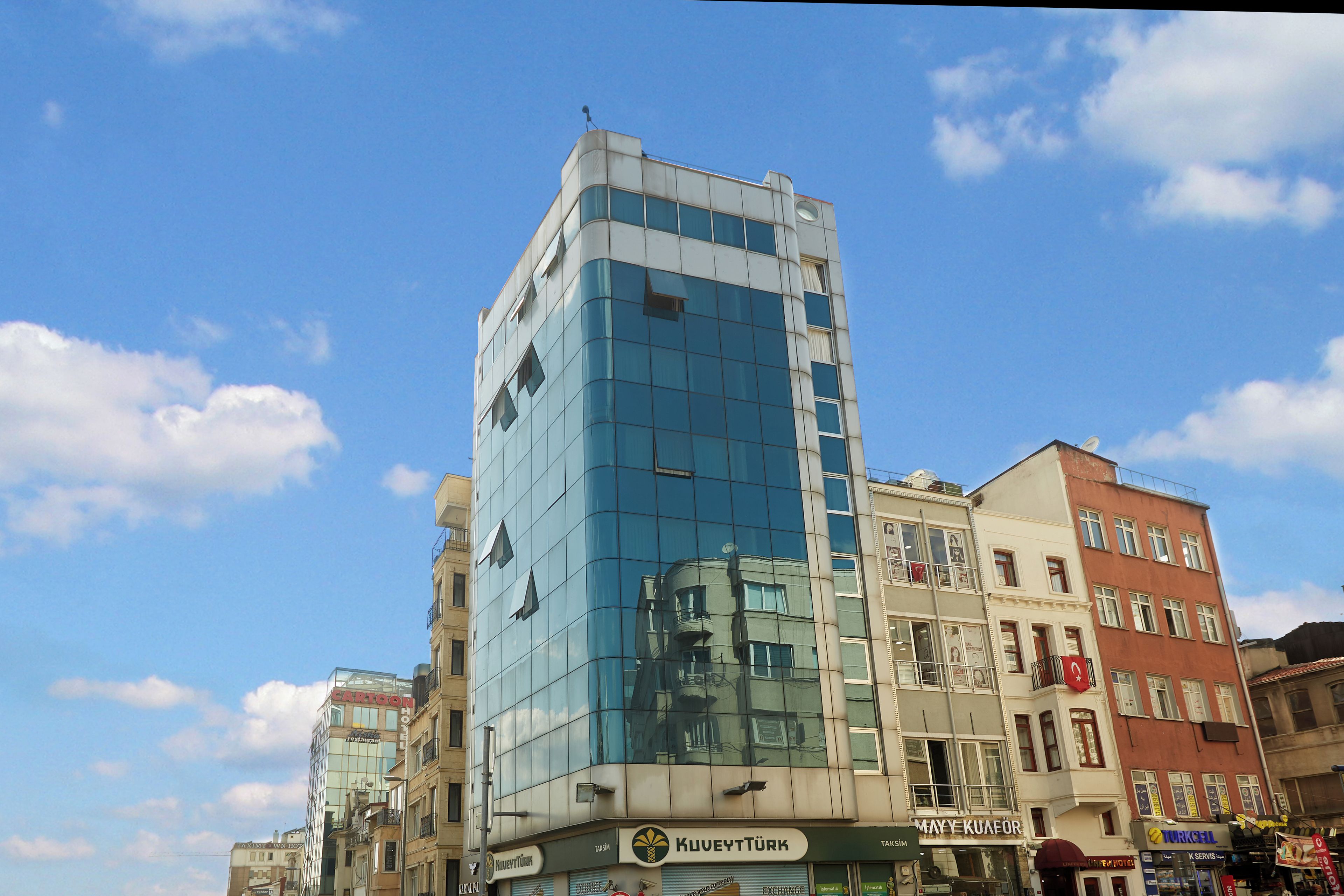 Un immeuble à plusieurs étages doté d’une façade en verre et de plusieurs boutiques situées au rez-de-chaussée.