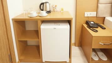 Une petite cuisine équipée comprenant un réfrigérateur, une machine à café et une petite table avec des tasses et un verre.
