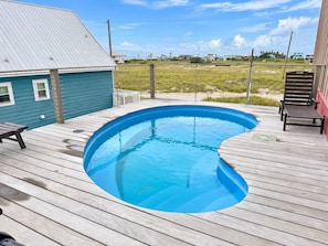 Ein Schwimmbecken auf einer Holzterrasse mit Blick auf Häuser im Hintergrund.