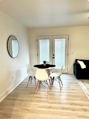 A dining area with a round table, four chairs, a mirror, and a black rug. - The Cute Cozy Loft - 206 (Clarksville)
