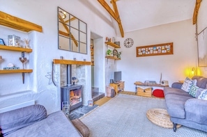 Ein gemütliches Wohnzimmer mit Kamin, Holzbalken und einem Fernseher.