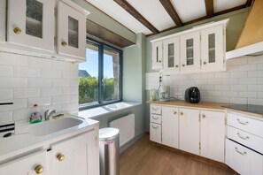 A kitchen with white cabinets, a window, a sink, and a coffee maker.