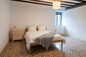 Une chambre à coucher avec un lit, une table de chevet, une lampe et une fenêtre.