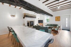 A spacious living area with a fireplace, a dining table, and a seating area with a sofa and chairs.