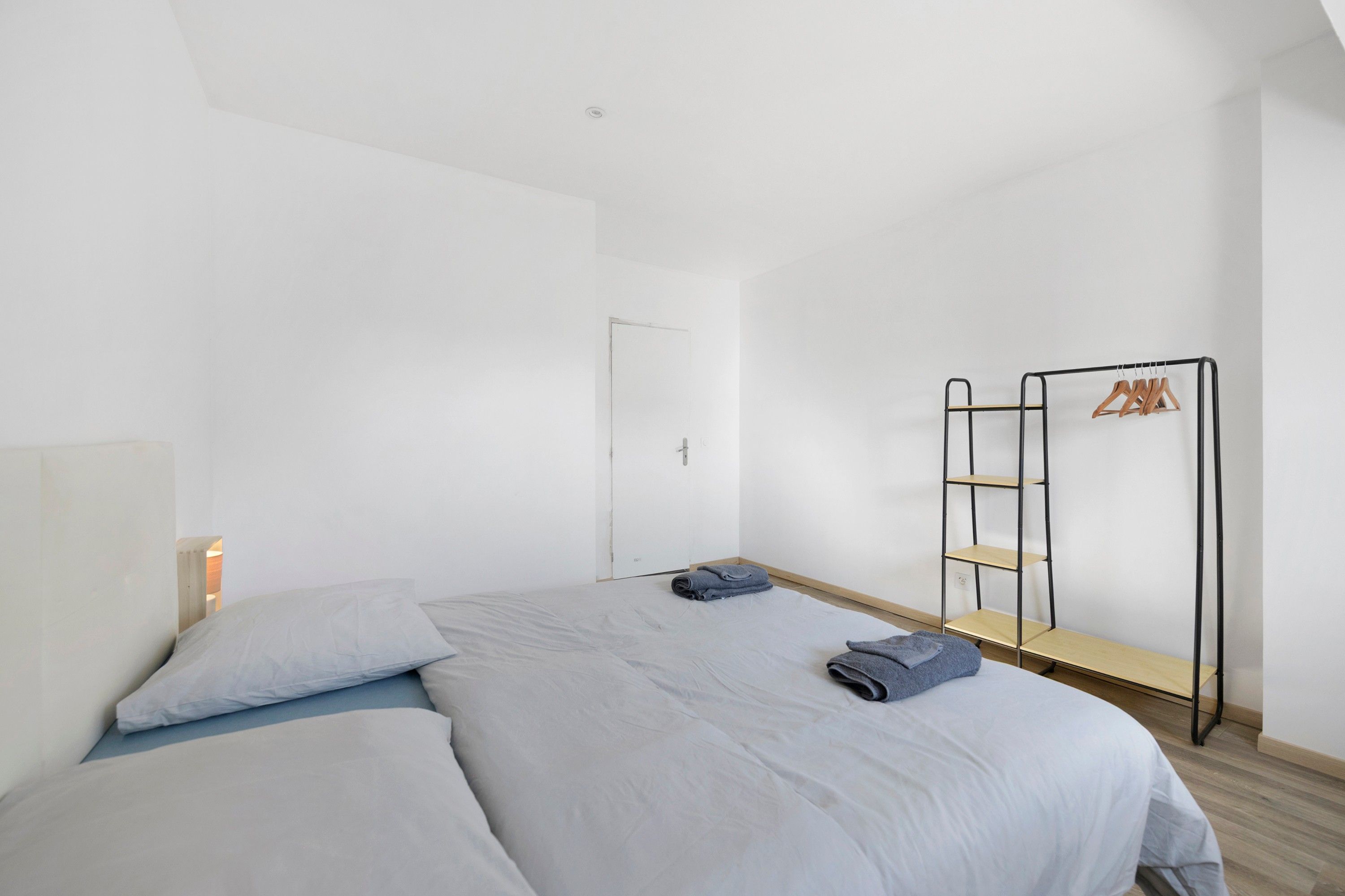 Quarto minimalista com cama, guarda-roupa e estante.