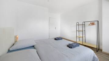 Quarto minimalista com cama, guarda-roupa e estante.
