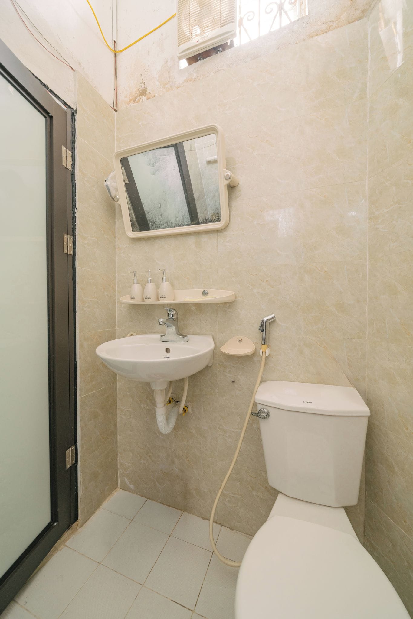 A bathroom with a sink, mirror, toilet, and a shower head.
