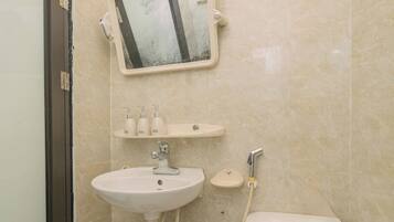 A bathroom with a sink, mirror, toilet, and a shower head.