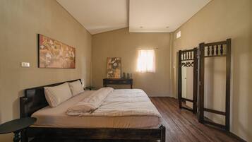 A bedroom with a bed, a nightstand, a dresser, a window with curtains, and a wardrobe.