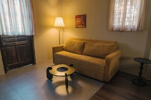 A cozy living room with a sofa, a small round table, a lamp, and a door. - Toffee Homestay Ninh Binh (Hoa Lu)