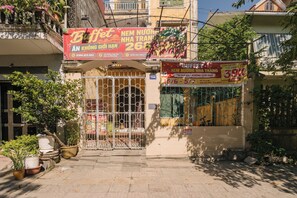 A storefront with a metal gate, potted plants, and promotional banners. - Toffee Homestay Ninh Binh (Hoa Lu)
