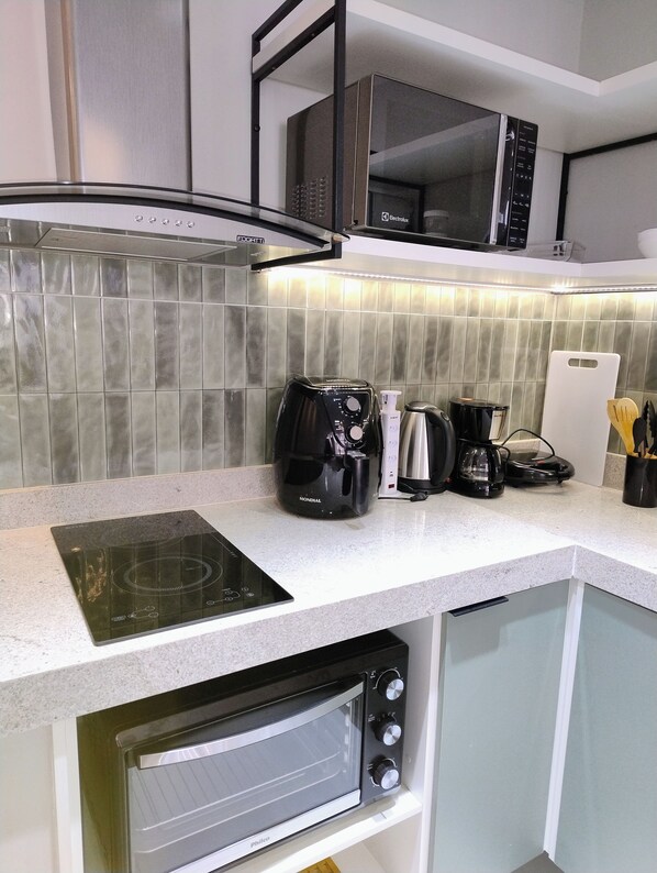 A kitchen with a built-in induction cooktop, a black coffee maker, a microwave, and a toaster.