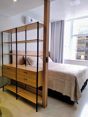A bedroom with a bunk bed, a bedside table, a chair, and a window with curtains.