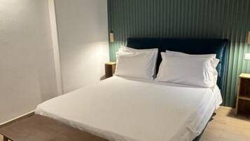 A neatly made bed with a dark headboard, a small wooden table, and two bedside lamps.