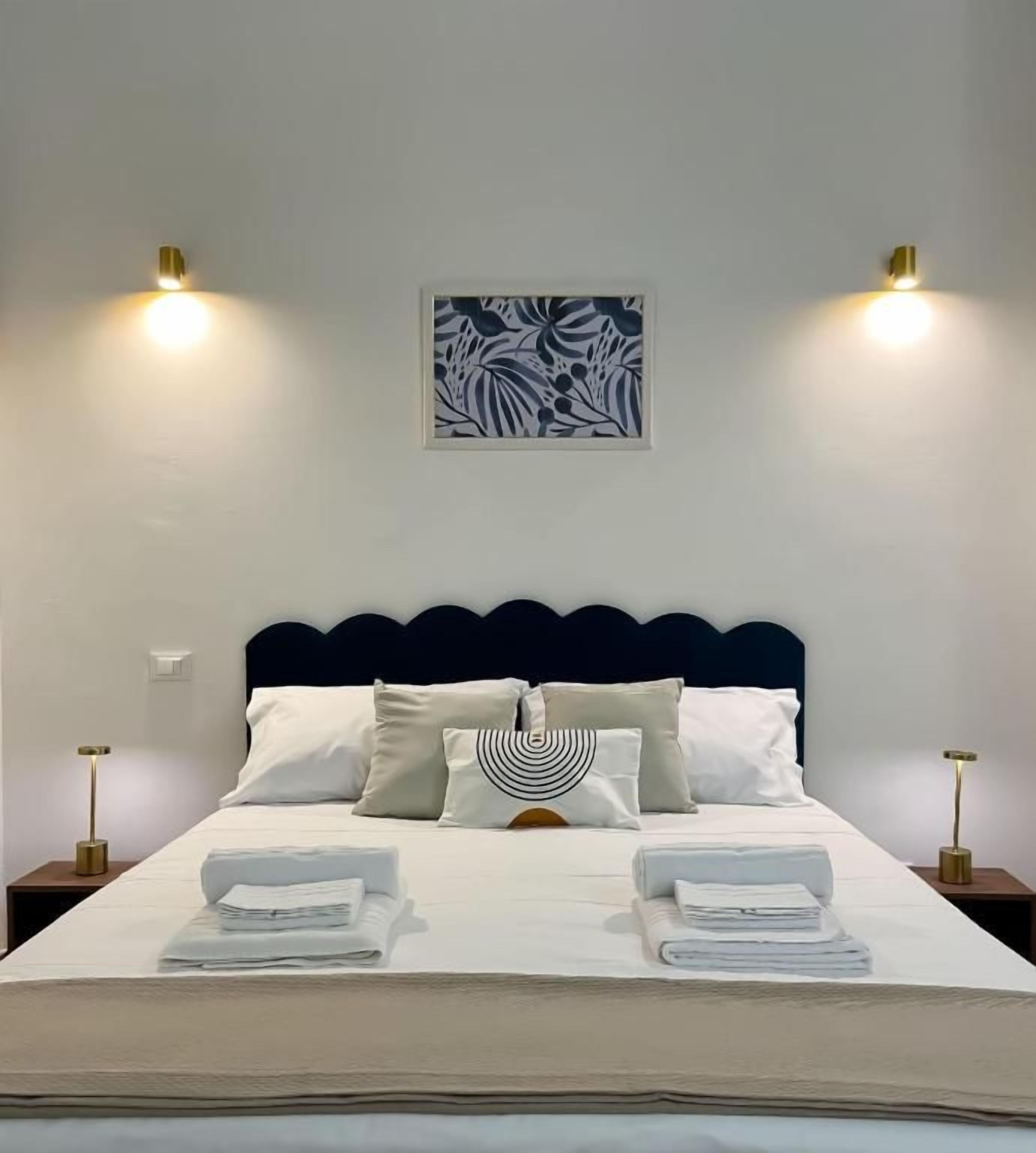 A neatly made bed with white linens, a headboard, and two bedside lamps.