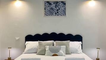 A neatly made bed with white linens, a headboard, and two bedside lamps.