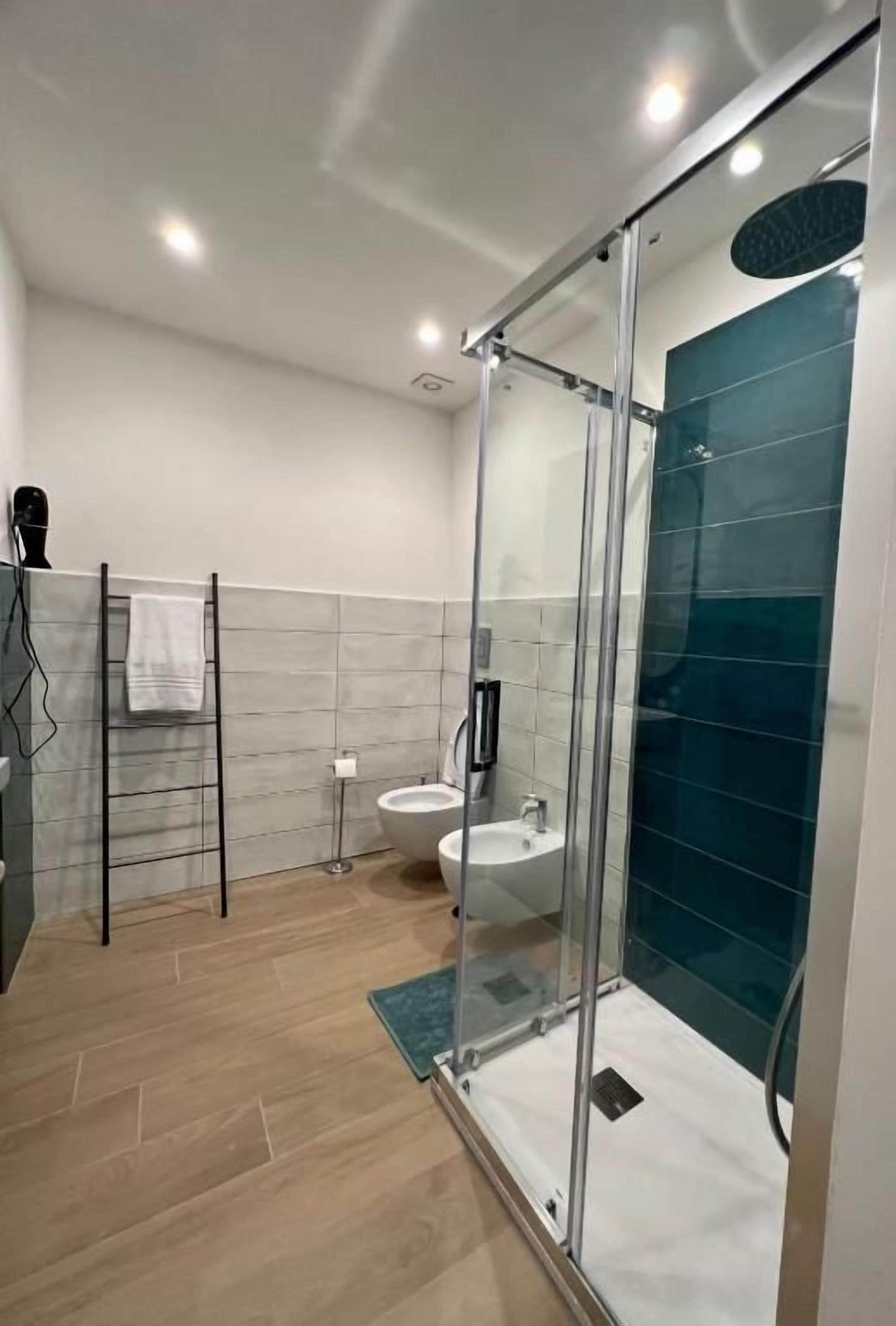 Un bagno moderno con doccia in vetro, lavabo e portasciugamani.