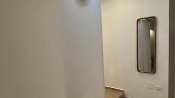 A hallway with a skylight, a wall-mounted mirror, and a light fixture.