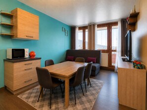 A compact living space with a dining table, chairs, a sofa, a television, and a microwave. - Apartment at the slopes - 8 guests (La Plagne)