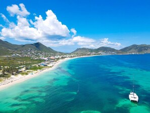 A coastal area with a beach, clear blue waters, and a sailboat. - Cocooning - 3 cozy bedrooms, direct beach access (Marigot)