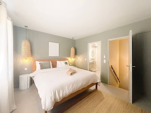 A bedroom with a bed, bedside lamps, a bathroom door, and a wardrobe. - Cocooning - 3 cozy bedrooms, direct beach access (Marigot)