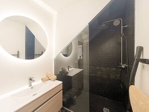 A modern bathroom with a large mirror, a sink, and a glass-enclosed shower area. - Cocooning - 3 cozy bedrooms, direct beach access (Marigot)