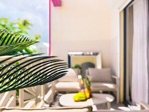 A balcony with a chair, a small table, and a potted plant. - Cocooning - 3 cozy bedrooms, direct beach access (Marigot)