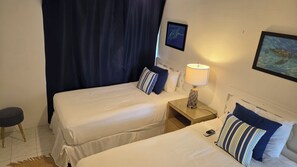 A hotel room with two beds, a nightstand, a lamp, a phone, and a picture on the wall. - Welcoming 3-bedroom house that is a 4 min walk to beach (Prospect)