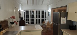 A compact kitchen with a refrigerator, a dining area with a chair, and a door leading to a balcony. - Welcoming 3-bedroom house that is a 4 min walk to beach (Prospect)