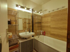 Ein modernes Badezimmer mit einer Duschkabine aus Glas, einem weißen Waschbecken und einer Badewanne.