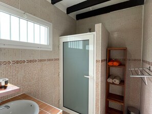 A bathroom with a shower, a sink, and a window.