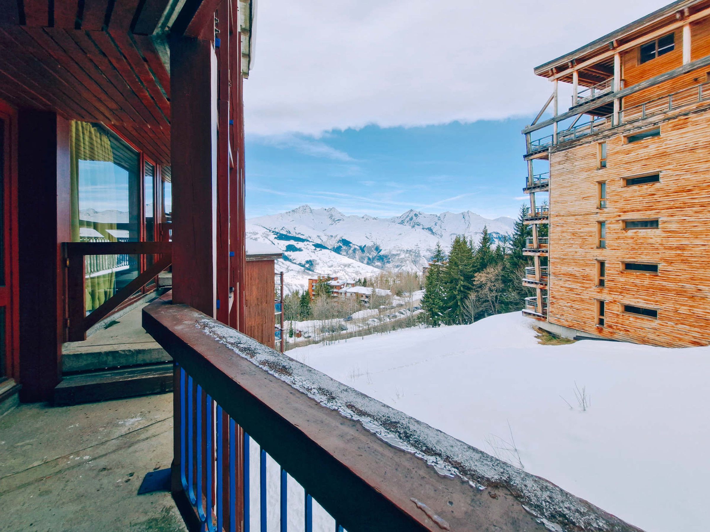 A wooden building with a balcony overlooking a snowy mountain landscape.