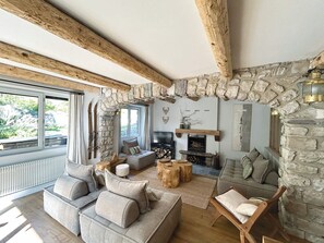 A cozy living room with a stone fireplace, a sofa set, and a television. - Spacious apartment - 12 guests (Valloire)