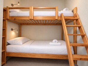 A bunk bed with a wooden frame, white bedding, and a ladder. - Cozy apartment, mountain view (Méribel)