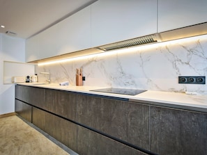 Eine moderne Küche mit Marmor-Spritzschutz, eingebauten Schränken und einer eleganten Arbeitsplatte.