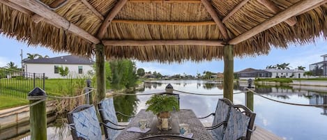 A covered outdoor seating area with a view of a water body and surrounding buildings.