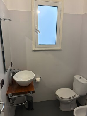 A bathroom with a white sink, toilet, and a window above the sink. - Room 'Camera Nix' with Wi-Fi and Air Conditioning (Siracusa)