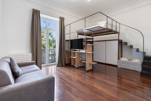 A modern living room with a sofa, a TV, a bunk bed, and a staircase. - Apartment 'Iris' with balcony, Wi-Fi and air conditioning (Siracusa)