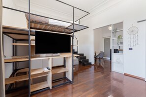 A modern interior with a bunk bed, a flat-screen TV, and a staircase leading to another room. - Apartment 'Iris' with balcony, Wi-Fi and air conditioning (Siracusa)