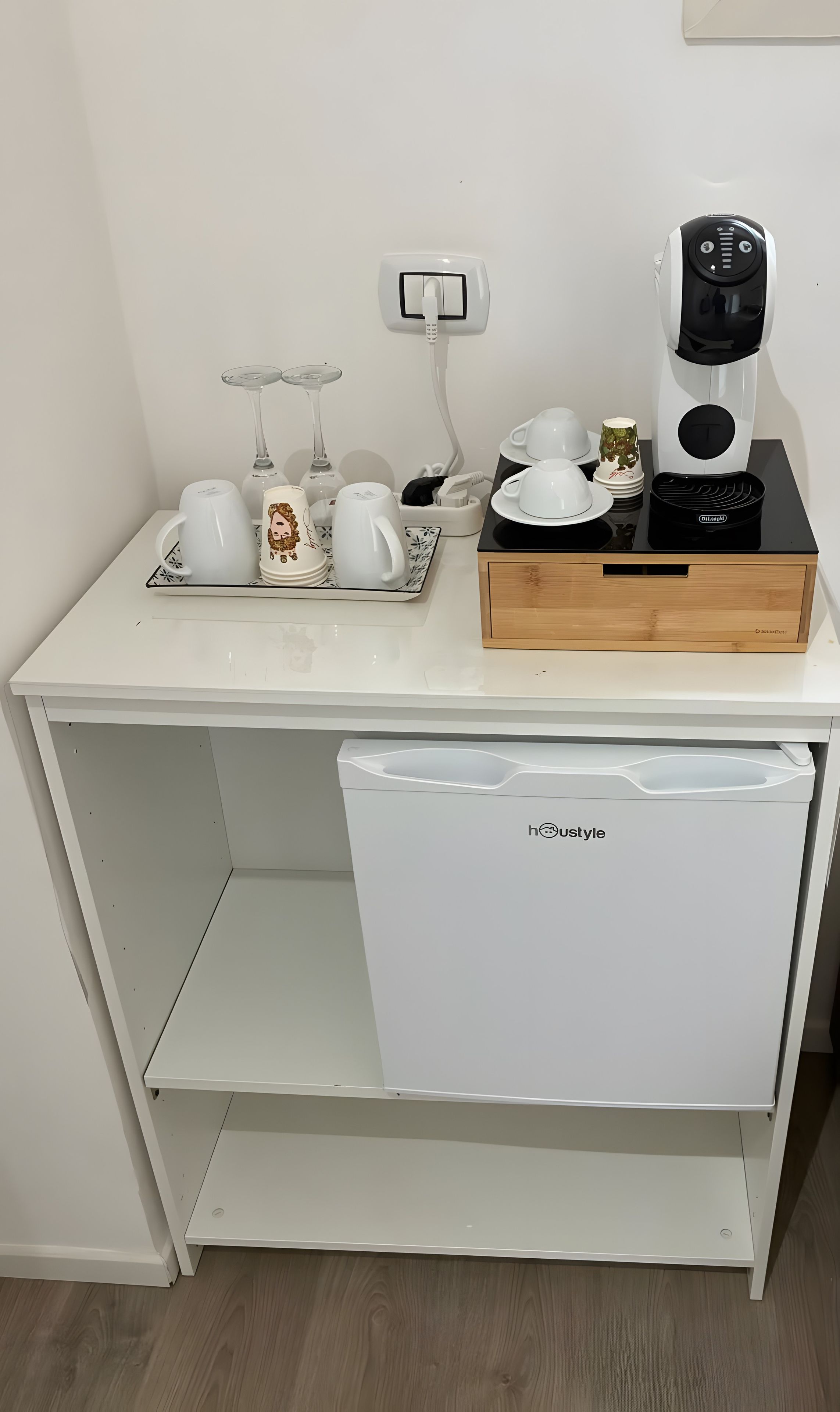 A compact kitchenette with a coffee maker, tea kettle, and a small refrigerator.