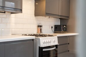A kitchen with a white countertop, a stove, an oven, and a toaster. - Cleethorpes 3-Bed House | Garden | Sleeps 6 (Cleethorpes)