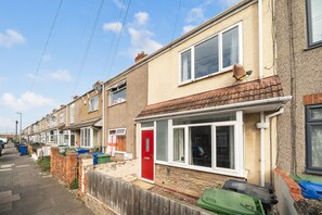A row of terraced houses with front doors, satellite dishes, and trash bins. - Cleethorpes 3-Bed House | Garden | Sleeps 6 (Cleethorpes)