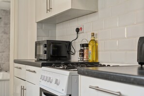 A kitchen with a stove, microwave, and a bottle of olive oil on the counter. - Grimsby 3-Bed House | Free Parking | Foosball (Grimsby)