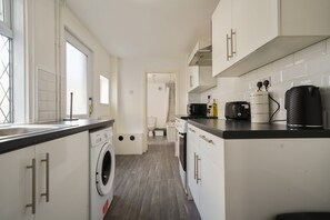 Eine kompakte Küche mit Waschmaschine, Mikrowelle und Kaffeemaschine.